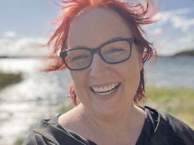 Elle står framför havet och hennes röda hår fladdrar i vinden.